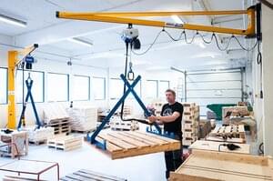 Mitarbeiter bedient Wandschwenkkran in Behindertenwerkstatt in Norwegen