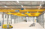Eine Industriehalle mit mehreren Laufkranen auf einer Bahn, im Vordergrund ein ABUS-Servicefahrzeug