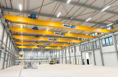 Eine Fabrikhalle mit fünf Einträger-Laufkranen auf gemeinsamer Bahn.