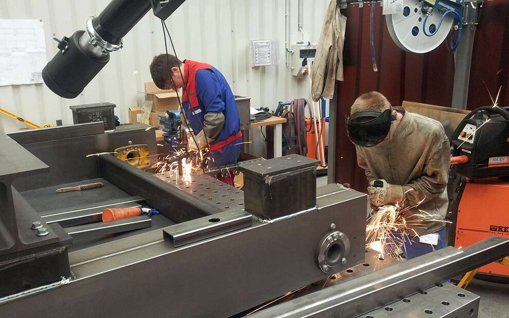 Auszubildende zu Konstruktionsmechanikern verschweißen vorgefertigte Baugruppen 