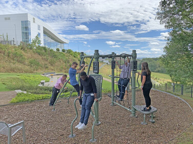 Vital Garten mit Blick auf das Kran-Haus, in dem ABUS Mitarbeiter an zahlreichen Fitness-Geräten Sport treiben